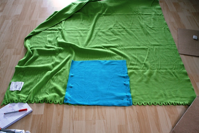 Cut out a square from one blanket and pin it at the bottom of the other blanket, centered.