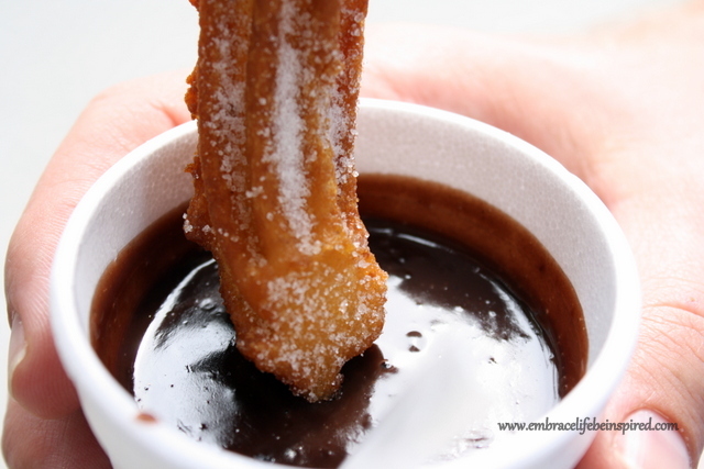 Churro being dipped in Chocolate